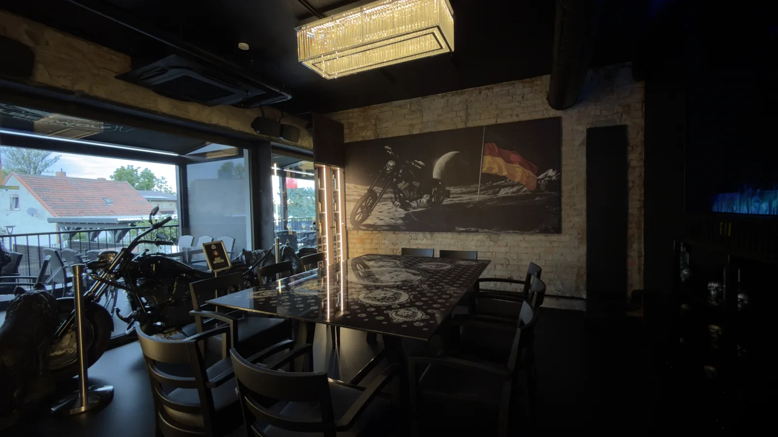 Dining table with wolf motifs in front of a mural of a motorcycle on the moon with a German flag