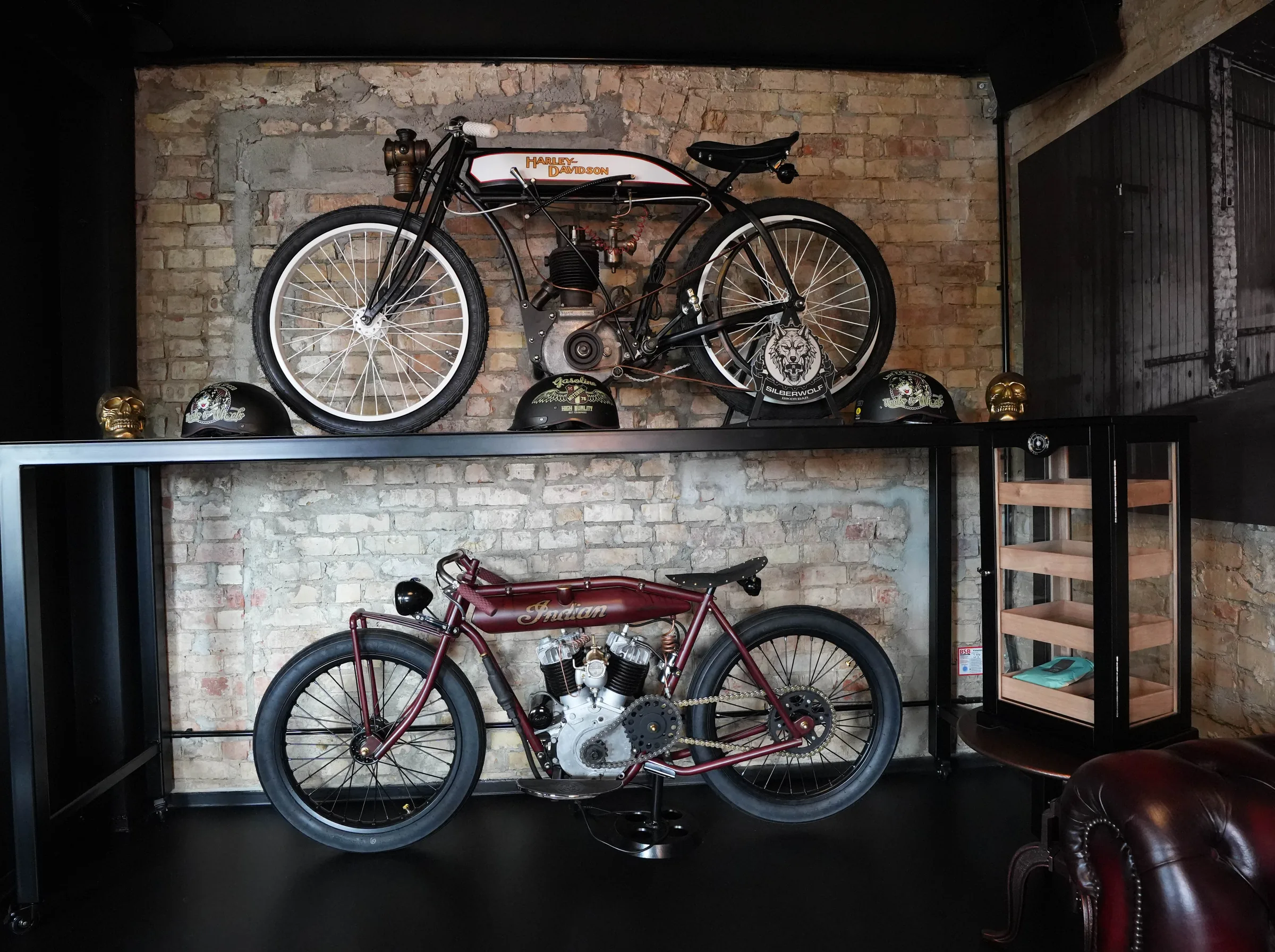 Oldtimer-Motorräder auf offenen Regalen an der Backsteinwand im Herrenzimmer