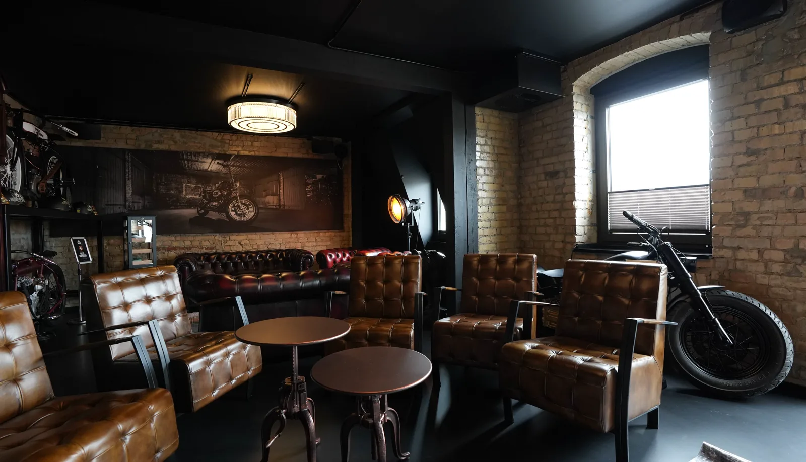Leather chairs around two round tables in the Herrenzimmer, a custom bike by the window and the studio lamp behind