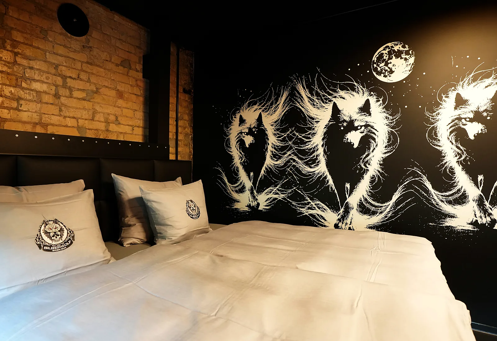 Zimmer Fat Boy: Bett unter dem Wolfs-Wandbild mit Vollmond