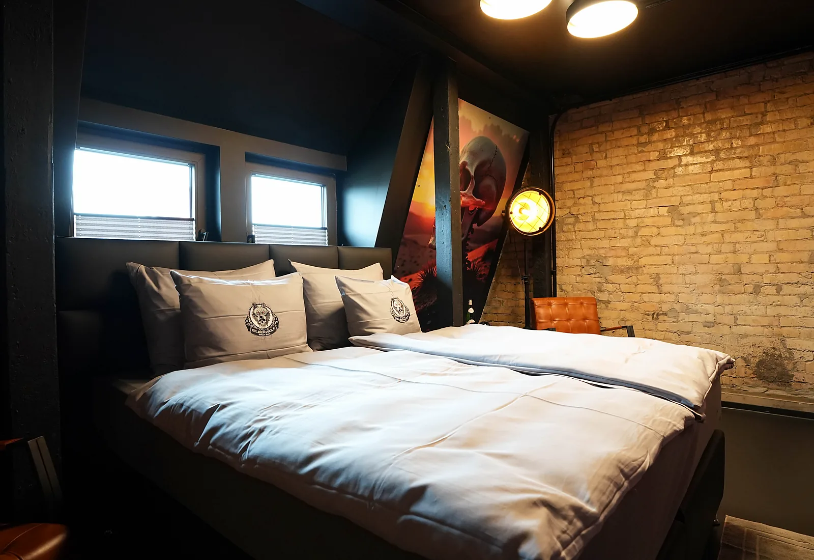 Zimmer Ghostrider: Boxspringbett vor Backsteinwand mit Fenstern