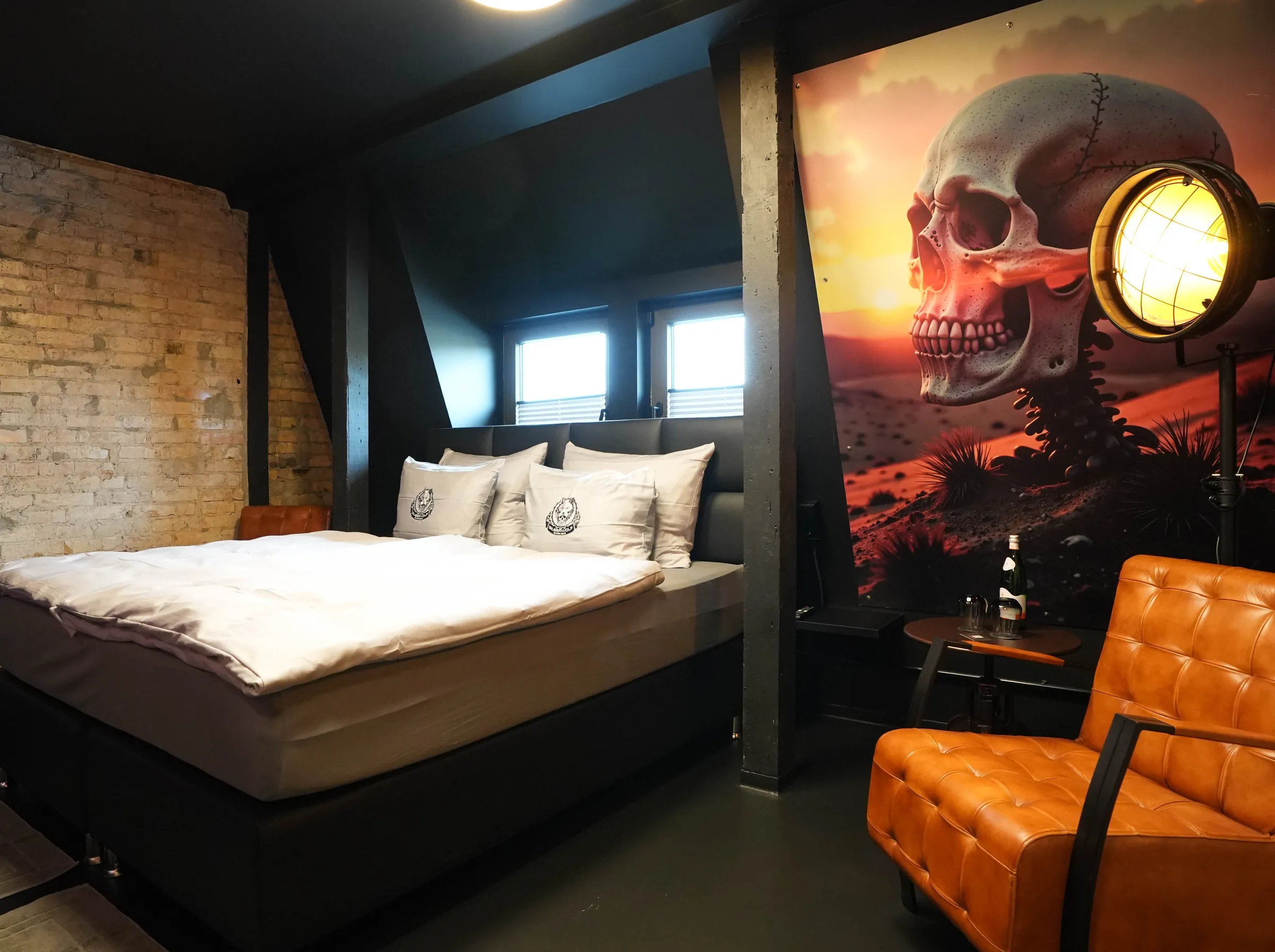 Ghostrider room — bed against a brick wall, next to it a large mural with a skull in the desert