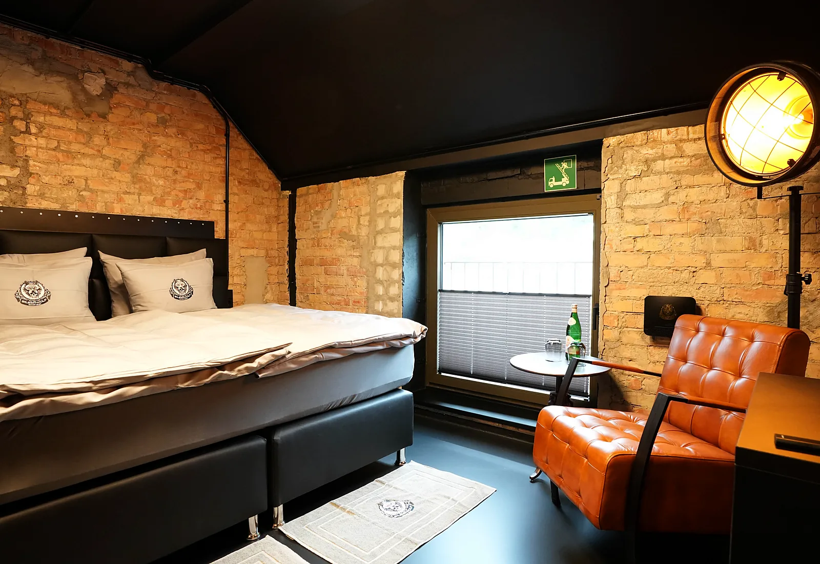 Route 66 room: box spring bed, leather armchair by the window and industrial spotlights