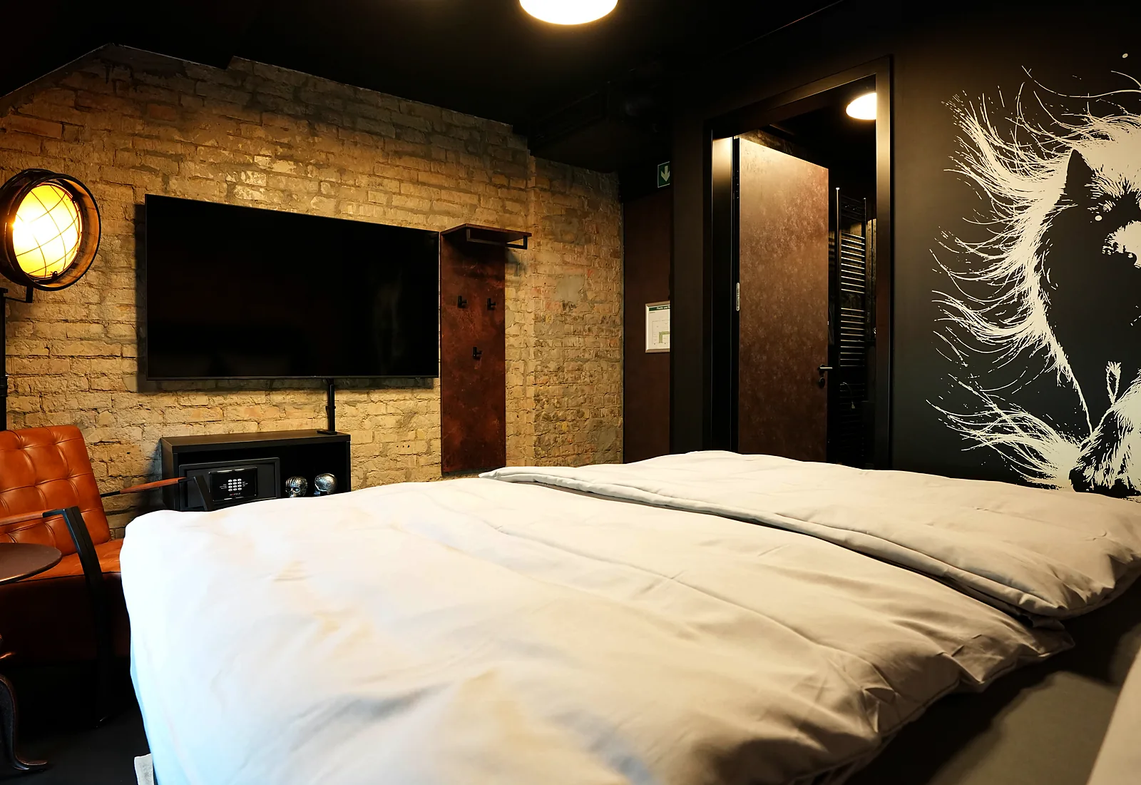 Zimmer Route 66: Bett unter dem Wolfs-Wandbild, Fernseher an der Backsteinwand