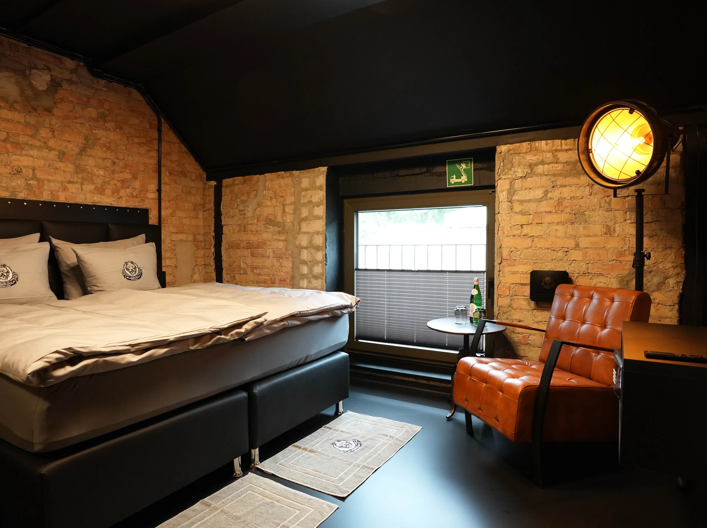 Route 66 room — box-spring bed, leather chair by the window and two industrial spotlights