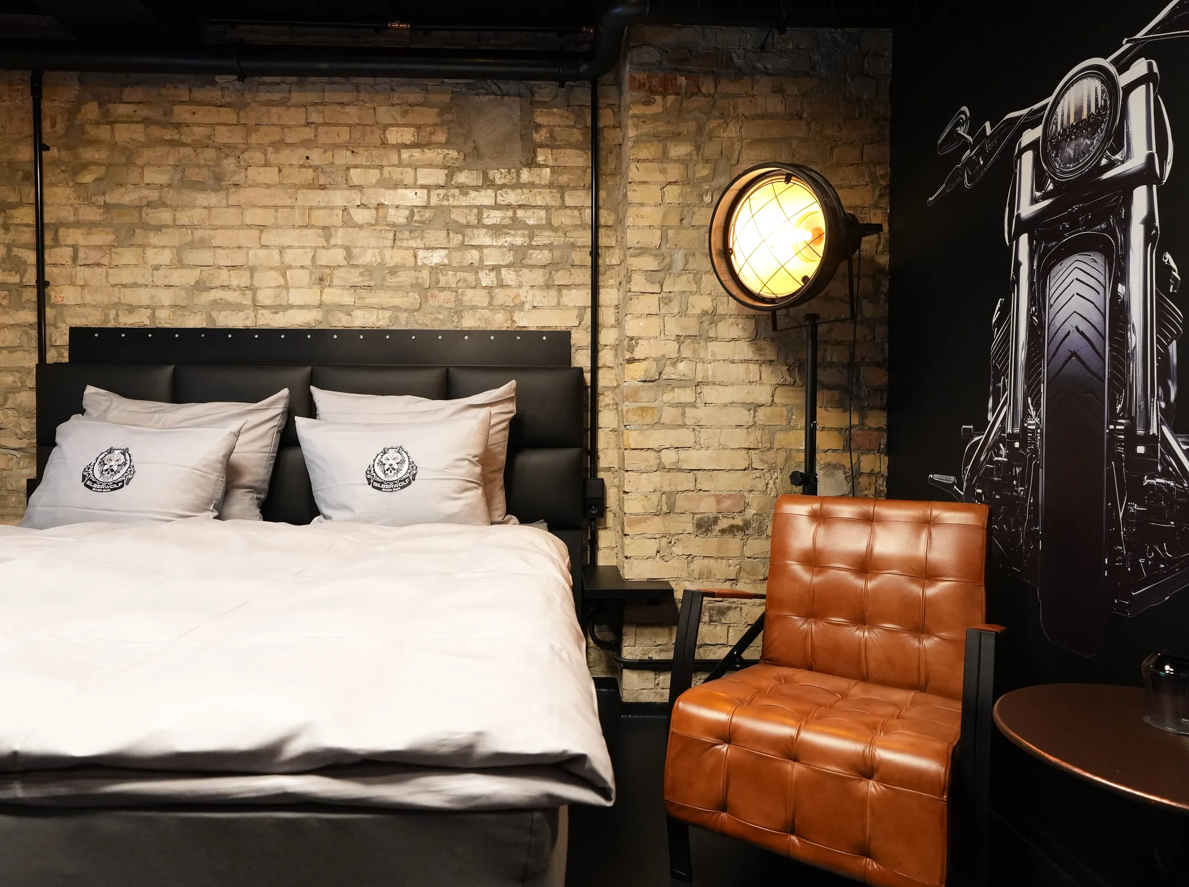 Sportster room — bed against a brick wall, next to it a large motorcycle mural