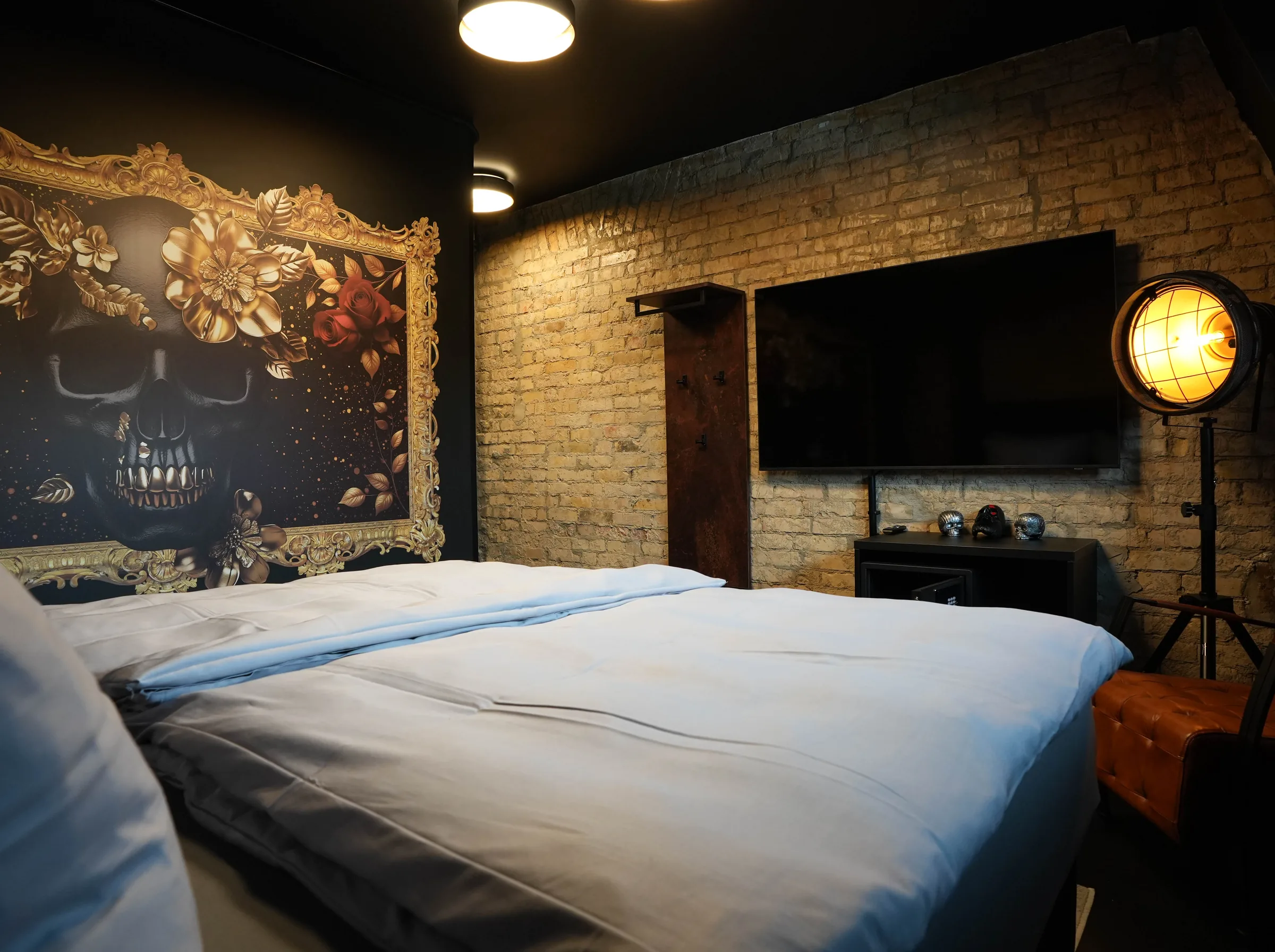 Street Bob room — mural with a skull in a gold frame, TV on the brick wall